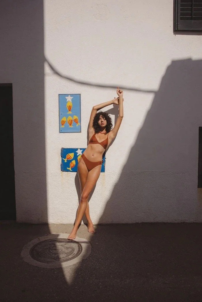 Woman in a classic rhythm swimsuit standing in front of a wall with colorful abstract art.