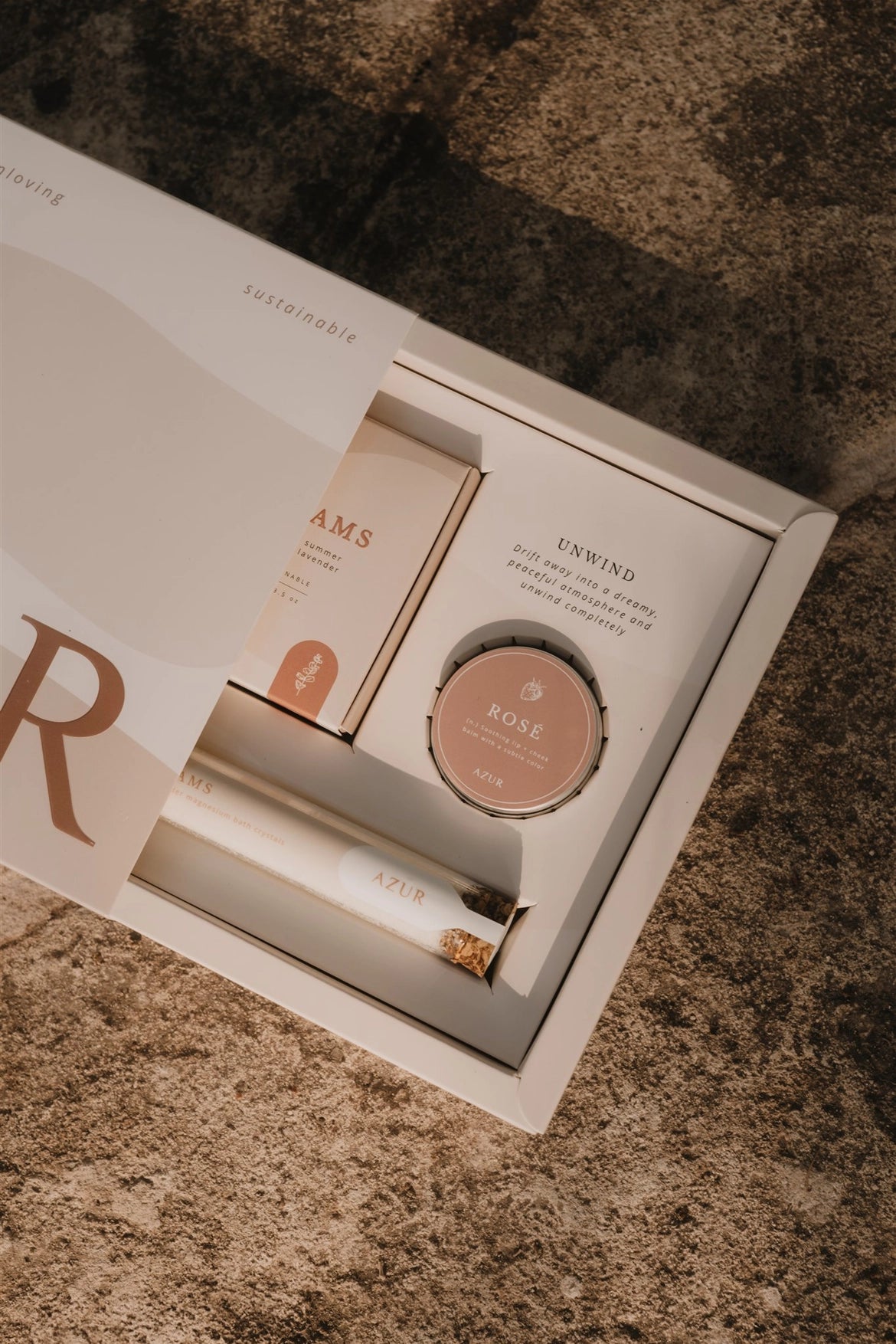 Azur Unwind gift set with a box on a textured surface, showing the natural body soap, bath salts and lip balm