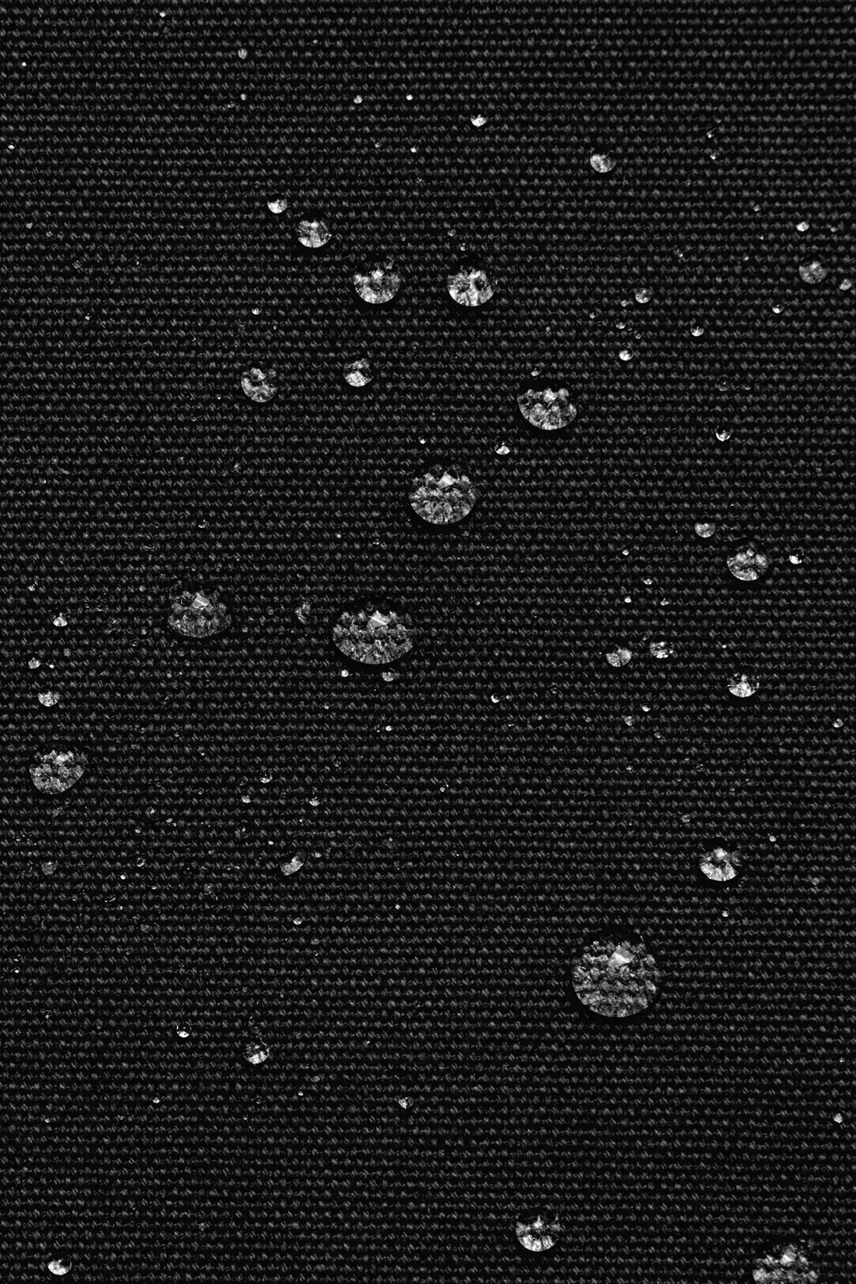 Water droplets on a black textured surface, waterproof backpack