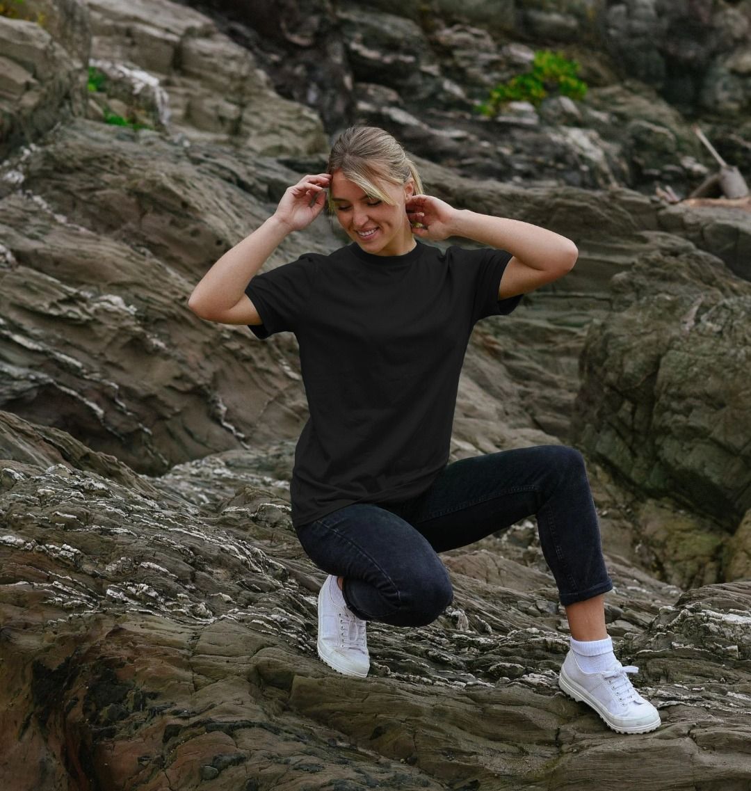 Person in black t-shirt and jeans squatting on rocky terrain