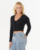 Woman wearing a rip curl black cardigan and blue jeans on a white background