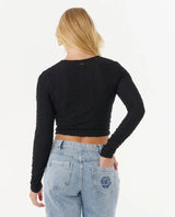 Person wearing a rip curl black long-sleeve crop top and light blue jeans on a white background
