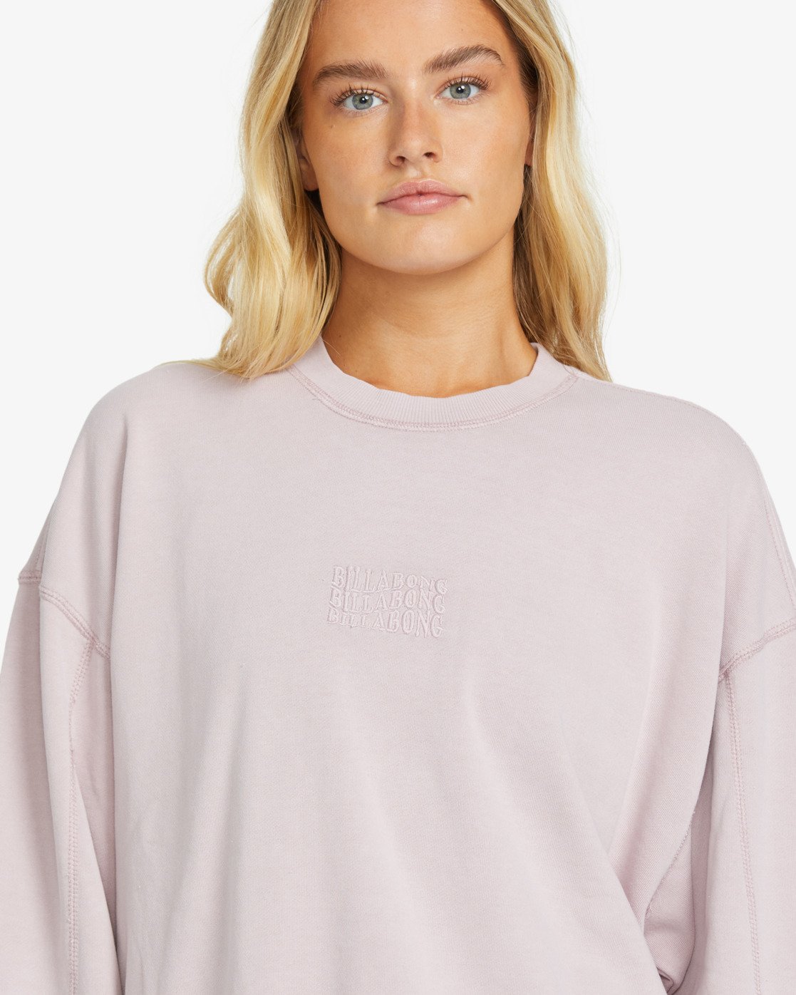 Person wearing a light pink billabong  sweatshirt with text on a white background