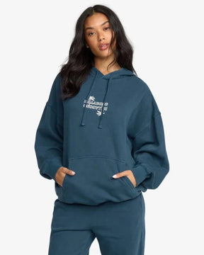 Woman wearing a teal billabong hoodie with a logo on a white background