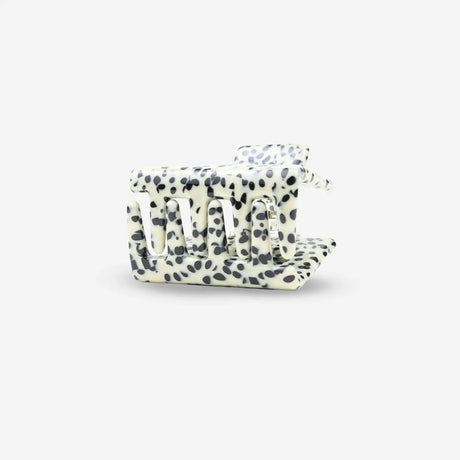 White hair clip with black polka dot pattern on a white background