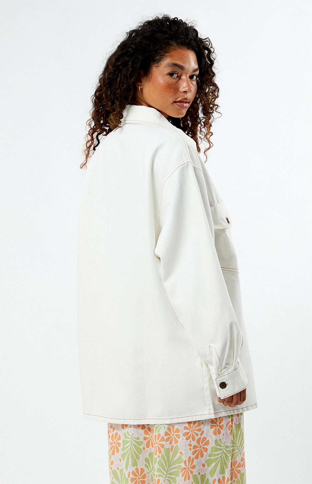 Woman wearing a rhythm camilla oversized white jacket with a floral skirt on a white background