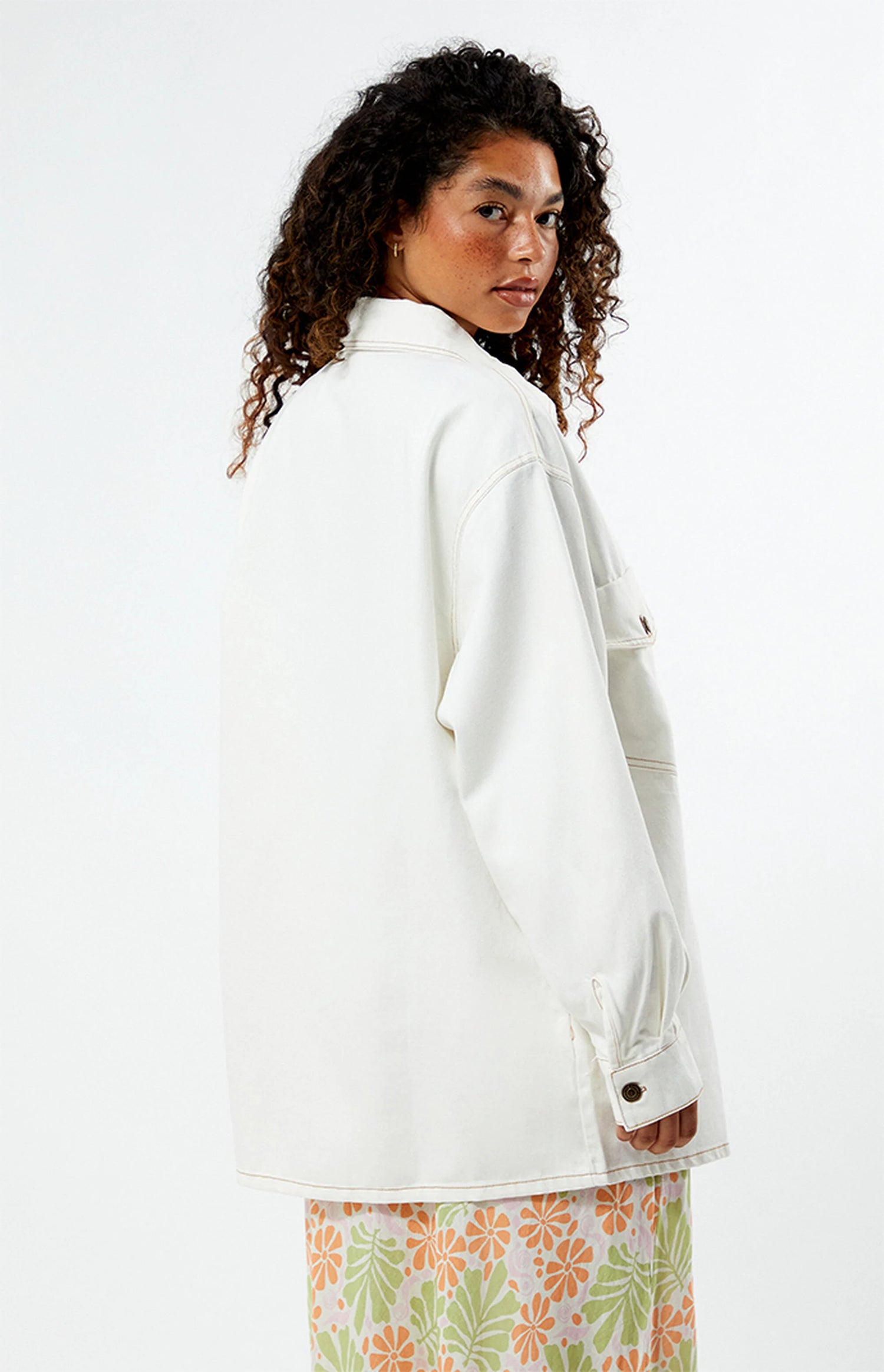 Woman wearing a rhythm camilla oversized white jacket with a floral skirt on a white background