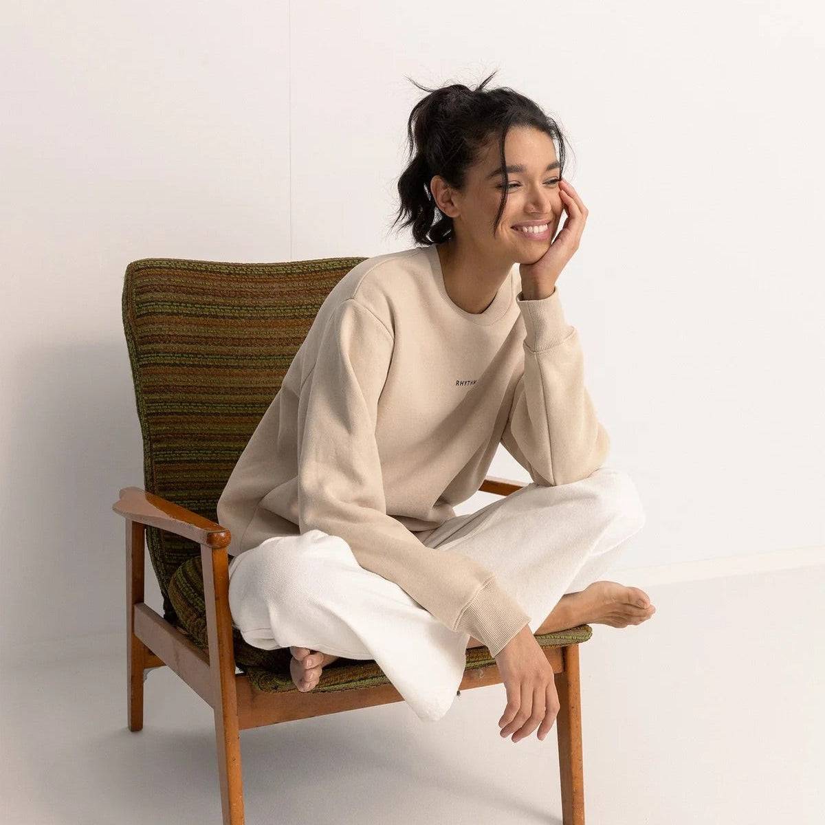 Woman sitting on a wooden chair with a woven backrest against a white background