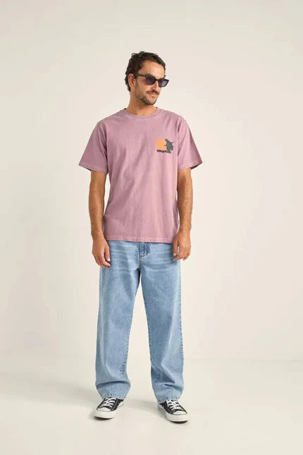 a man wearing melibea oceanides sunglasses, a rhythim tropic radio t-shirt and rvca denim jeans