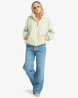 Woman wearing a billabong checkered hoodie and blue jeans on a white background